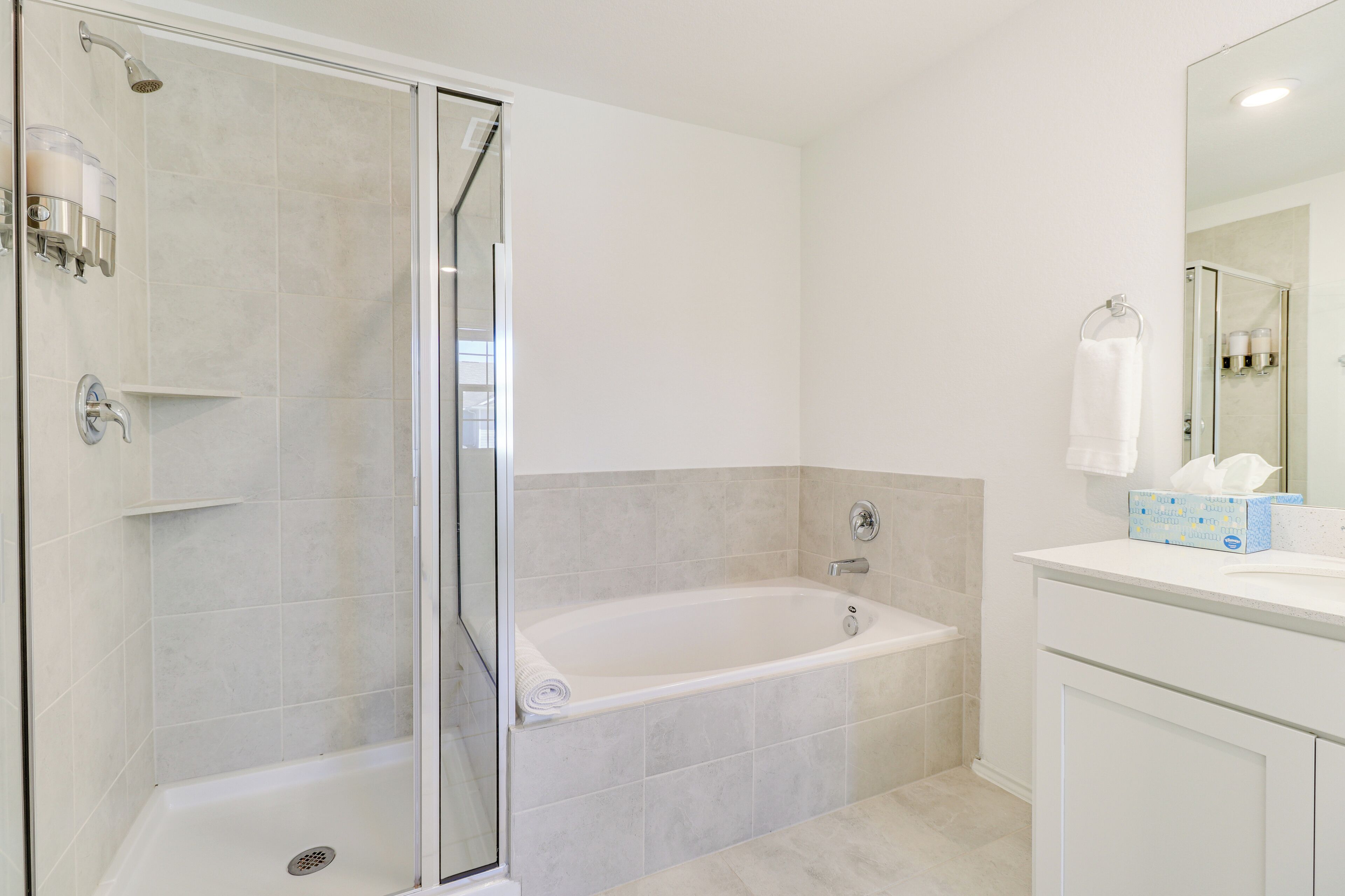 A modern bathroom with a glass-enclosed shower, a freestanding bathtub, and a vanity with a mirror.