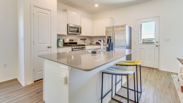 A modern kitchen with white cabinets, stainless steel appliances, and a central island with bar stools. - 12 Mi to Dtwn Austin: Quiet Home w/ Patio & Yard (Del Valle)