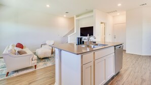 A modern kitchen with a central island, white cabinetry, and a built-in dishwasher. - 12 Mi to Dtwn Austin: Quiet Home w/ Patio & Yard (Del Valle)