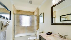 A bathroom with a shower, toilet, sink, and mirror. - Pool w/ Waterfall: Colorful Cape Coral Gem! (Cape Coral)