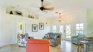 A spacious living room with a ceiling fan, a sofa, a chair, and a dining area with a table. - Pool w/ Waterfall: Colorful Cape Coral Gem! (Cape Coral)
