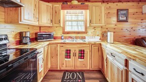 Une cuisine de style rustique, avec des murs en bois, un poêle, un four à micro-ondes et des armoires en bois.