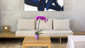 A modern living room with a beige sofa, a wooden coffee table, and a purple orchid plant. - Two-bedroom Villa with a private heated pool (Thasos)