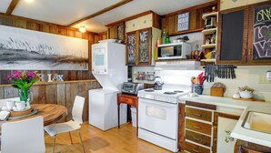 A kitchen with wooden cabinets, a refrigerator, a stove, and a microwave. There is a chalkboard with writing on the wall. - Sandy Toes Loft w/ Ocean Views in Moclips! (Moclips)