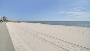 A wide, sandy beach with a clear sky and calm sea.