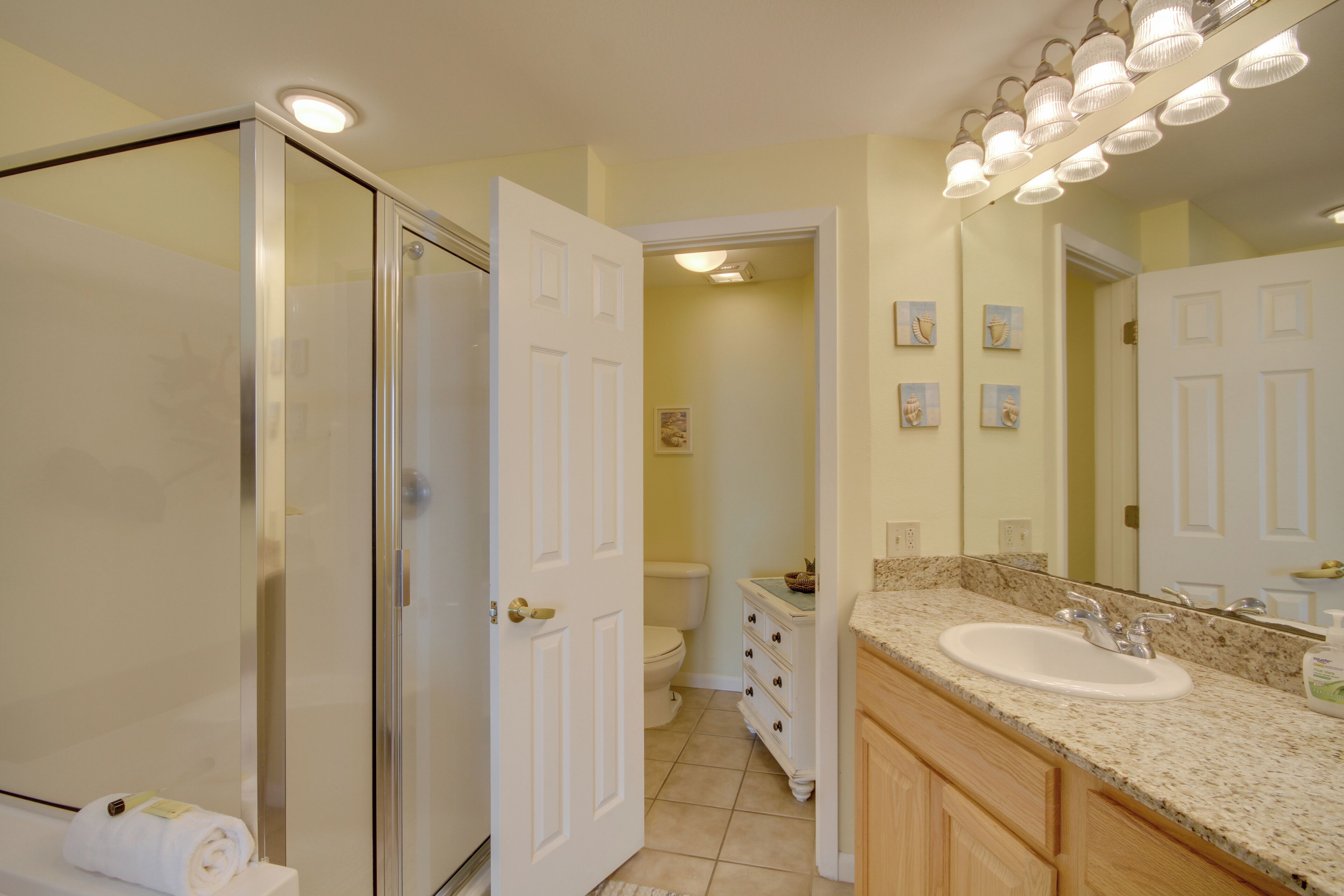 Un baño con cabina de ducha de vidrio, un lavabo blanco y un mueble de tocador con cajones.
