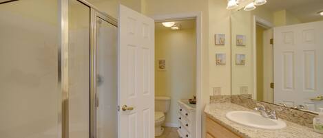 Un baño con cabina de ducha de vidrio, un lavabo blanco y un mueble de tocador con cajones.