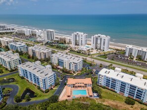 Ein Hochhaus-Hotel mit mehreren Etagen, einem Schwimmbad und Blick auf den Strand.