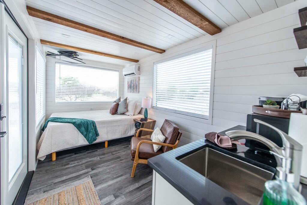 Une petite pièce comprenant un lit, une chaise, un lavabo et une fenêtre.