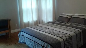 A bedroom with a bed, curtains, and a small table. - 6 bedroom 2 bath country retreat
 (New Brunswick)