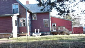 A two-story house with a red exterior, a front porch, and a small deck. - 6 bedroom 2 bath country retreat
 (New Brunswick)