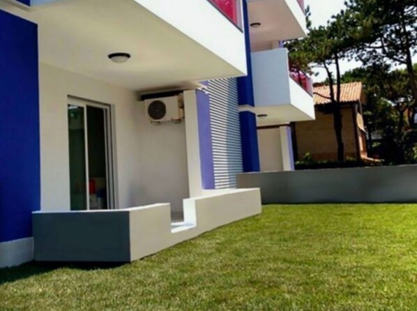 A modern building with a flat roof, a flat facade, and a small front porch with steps leading to the entrance. - Garden Retreat Steps From the Pool (San Michele al Tagliamento)