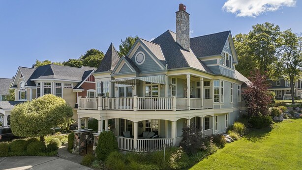 A large, two-story house with a balcony and a stone chimney.