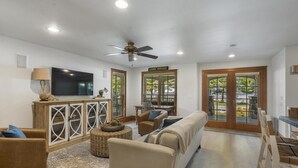 A living room with a sofa, chairs, a TV, and a ceiling fan.