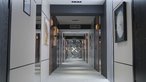 A modern, well-lit hallway with a central decorative wall, flanked by framed artwork and illuminated by linear light fixtures. - Qaragat (Jalal-Abad)