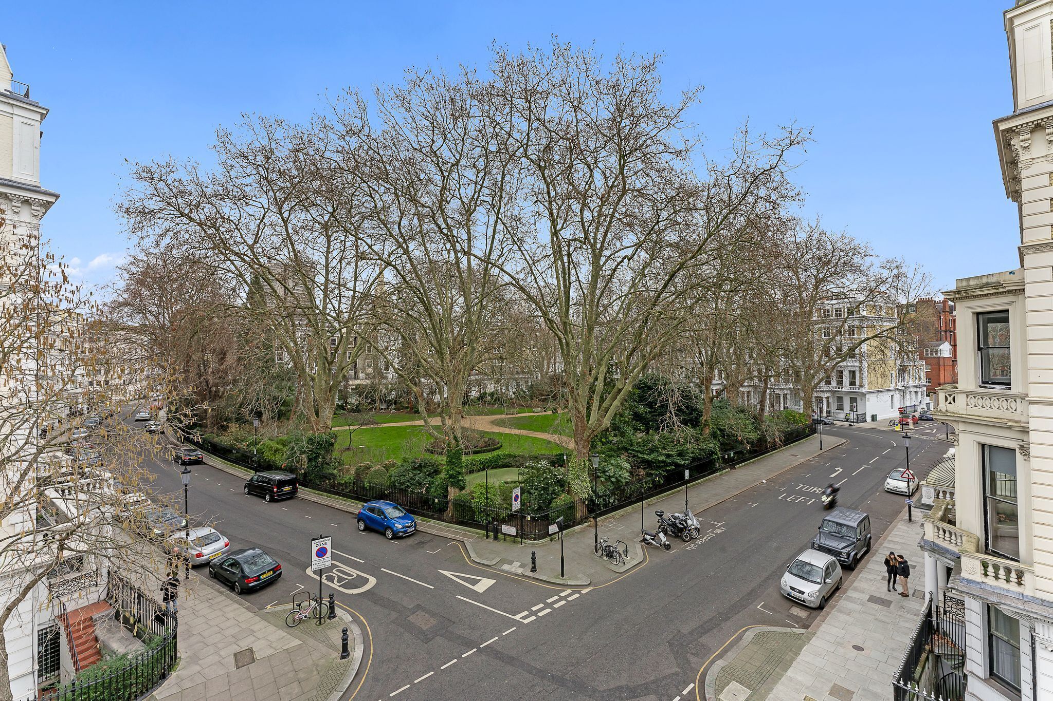 A street view with parked cars, a bicycle, and a pedestrian crossing.