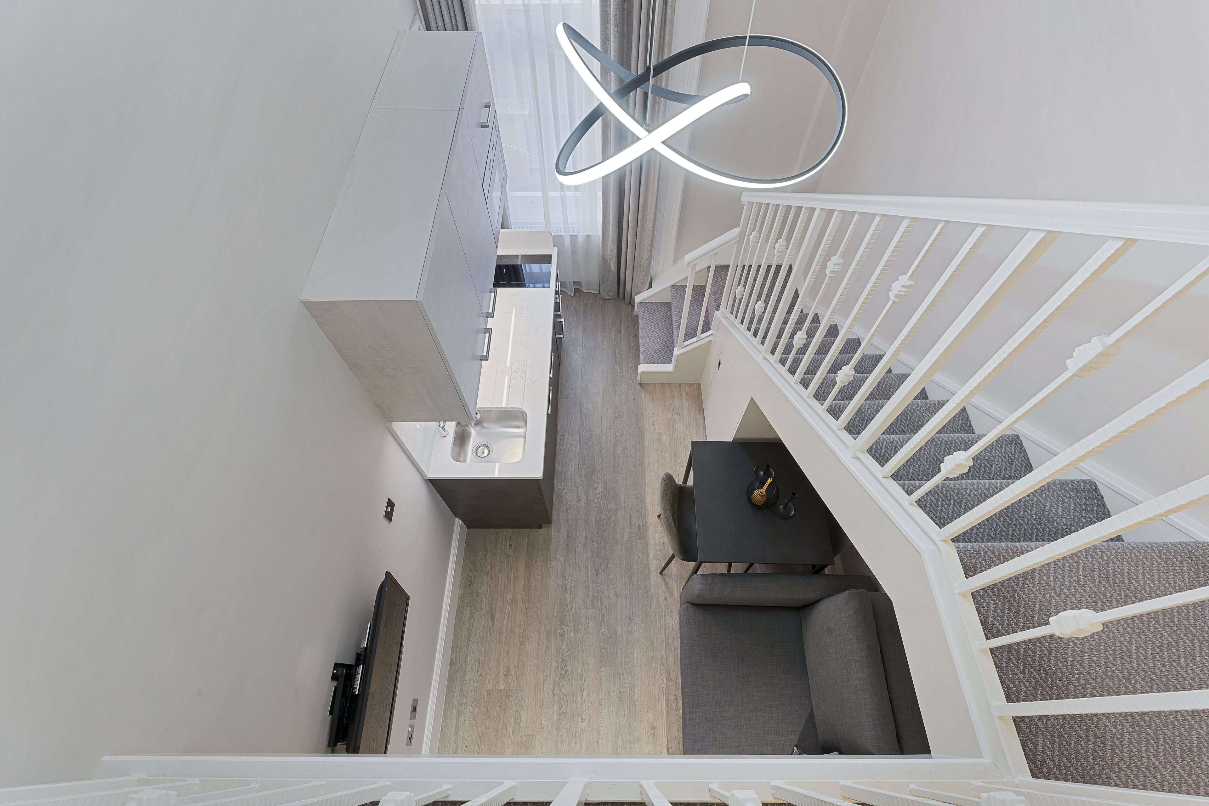 Un interior moderno con una escalera, una zona de comedor y una cocina.