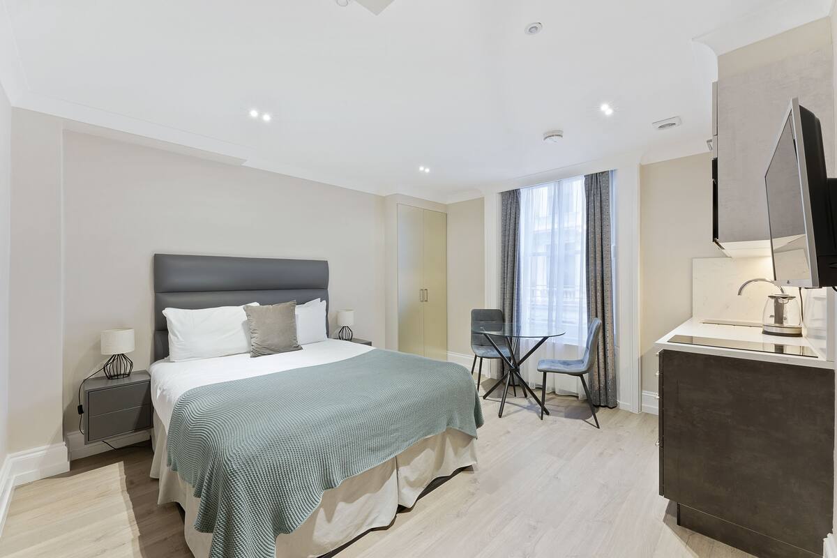 A modern hotel room with a large bed, bedside tables, a desk, and a TV.