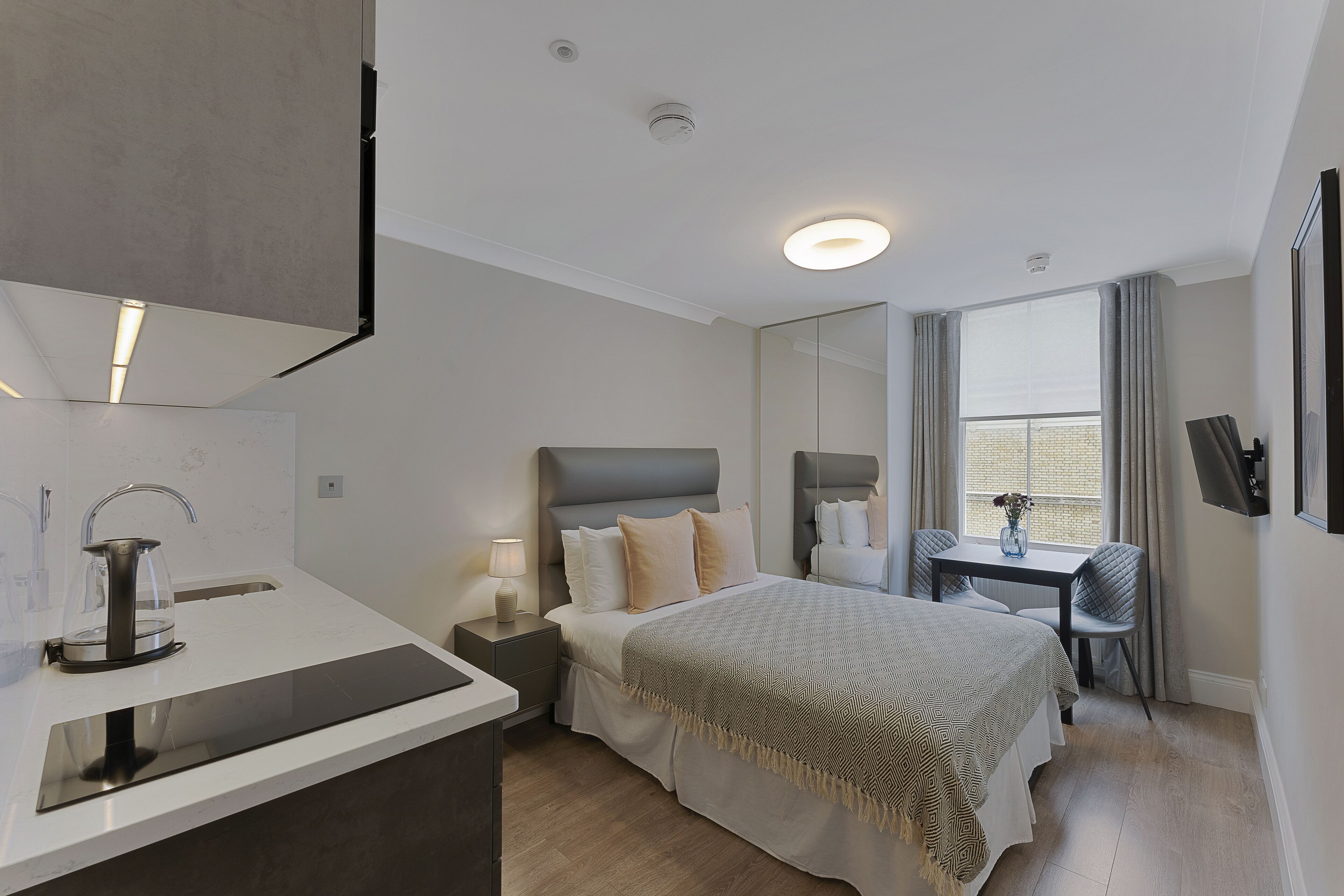 Une chambre d’hôtel moderne, équipée d’un lit, d’une table de chevet, d’une lampe et offrant une vue sur l’extérieur.
