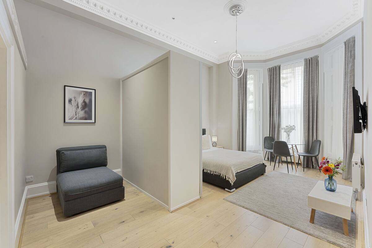 A modern bedroom with a bed, a sofa, a desk, and a chair.