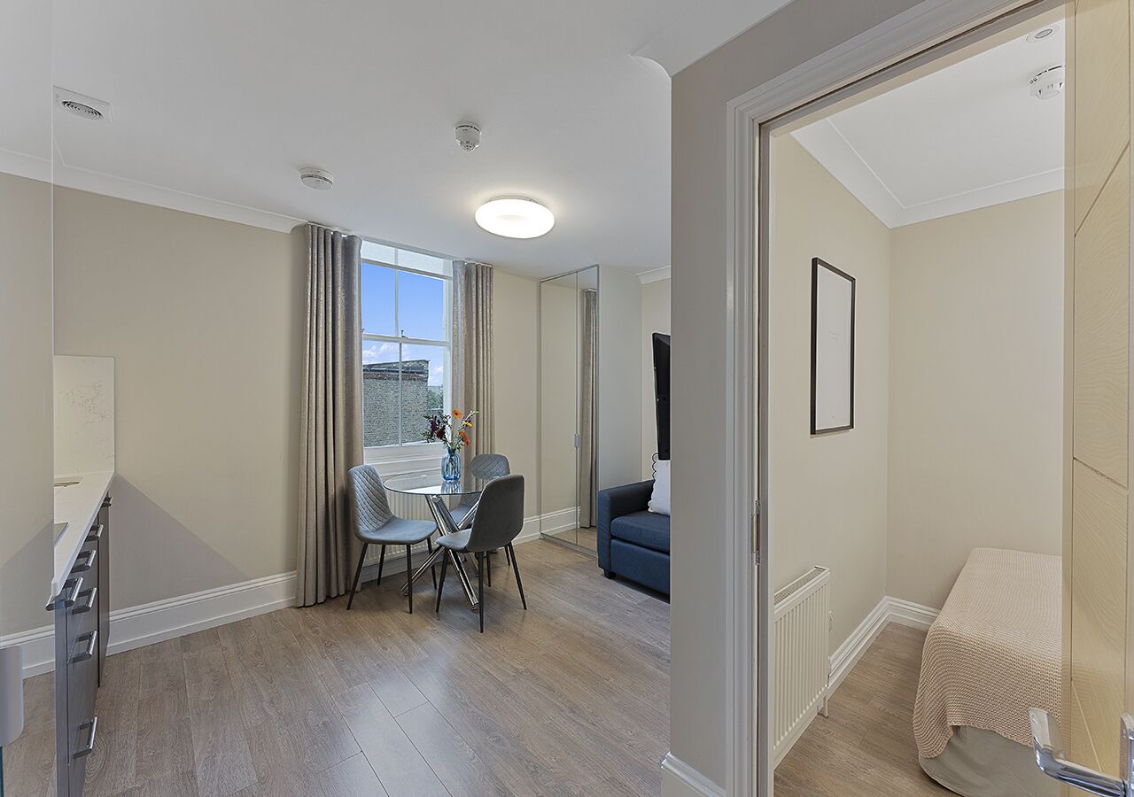 A modern apartment with a dining area, a living room, and a small bedroom.