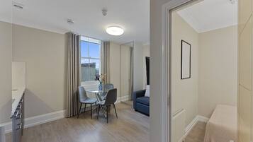 A modern apartment with a dining area, a living room, and a small bedroom.
