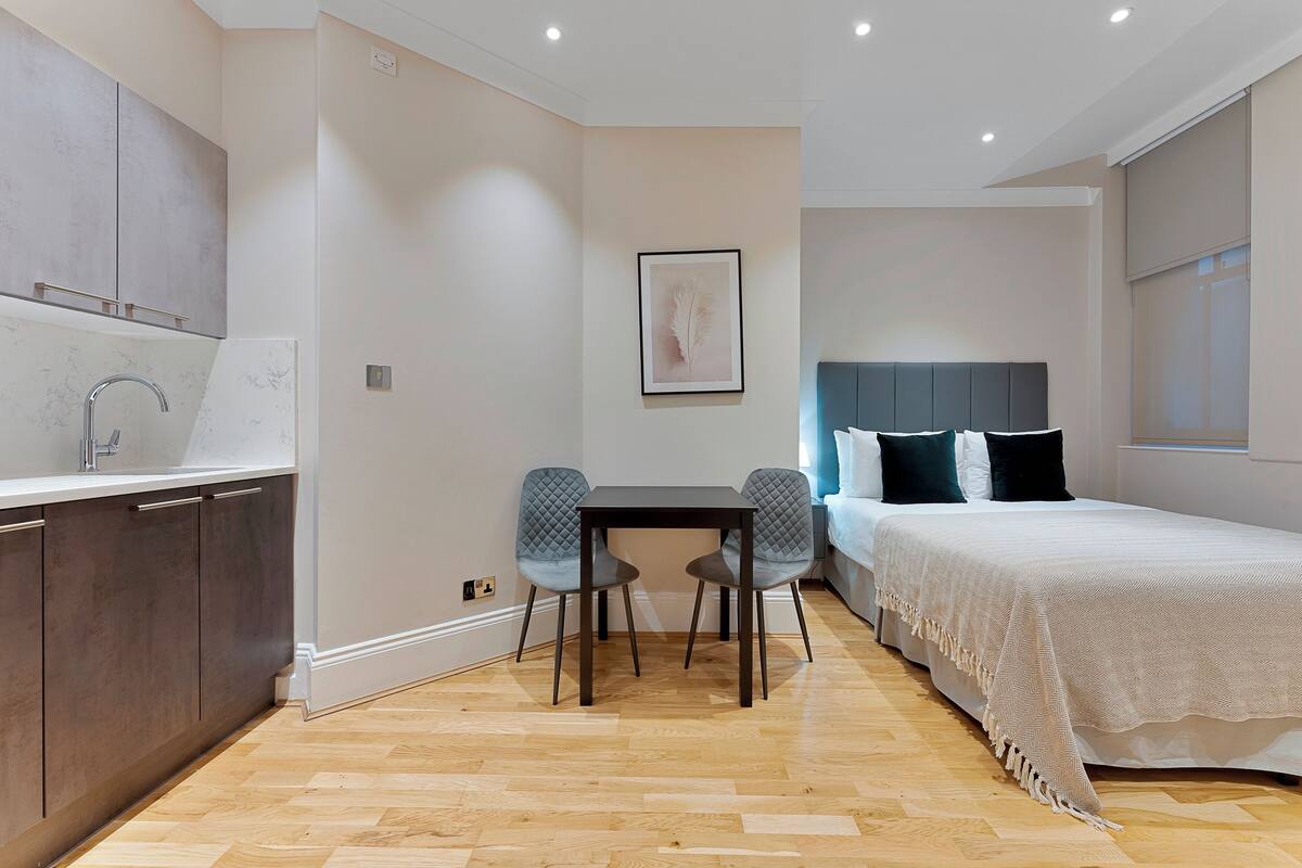 A modern bedroom with a bed, bedside table, and two chairs.
