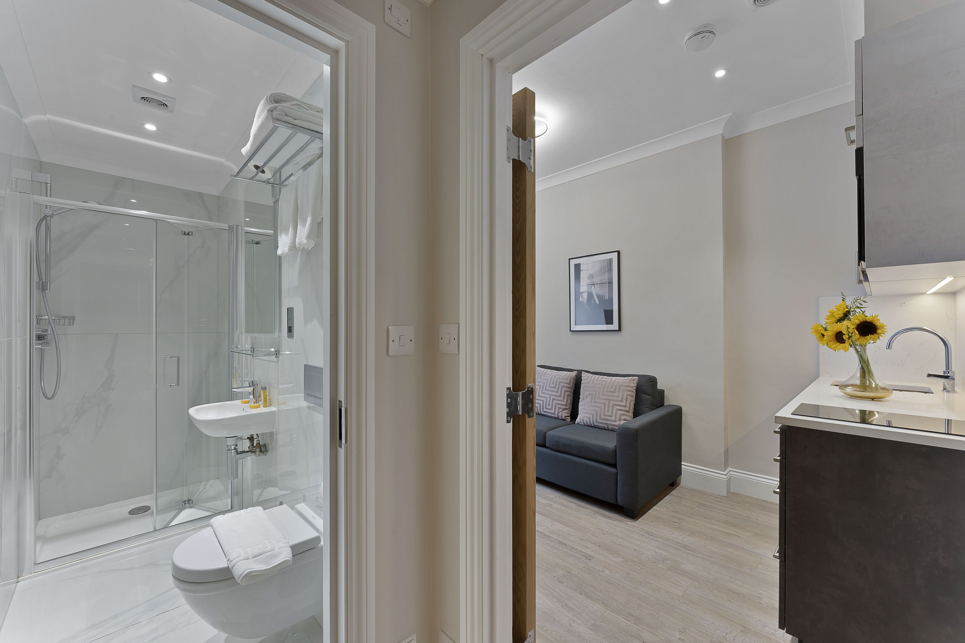Un baño moderno con cabina de ducha de vidrio, un lavabo blanco y un inodoro.