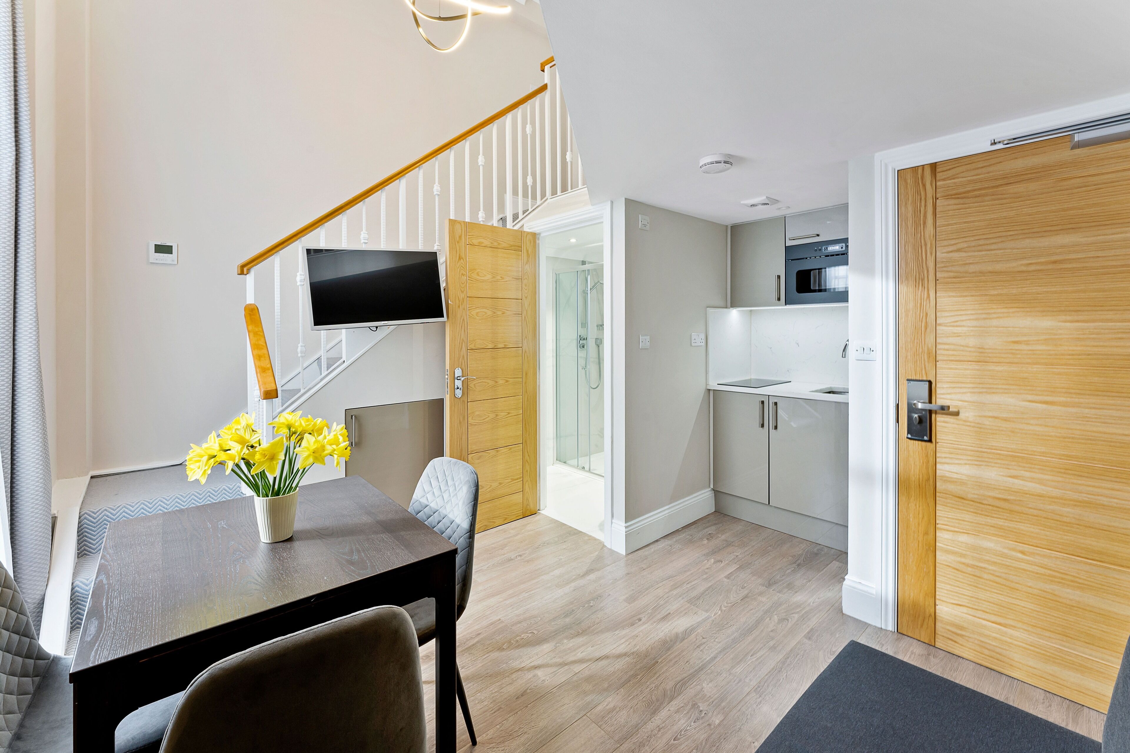 A modern kitchen with white cabinets, a built-in oven, and a microwave.