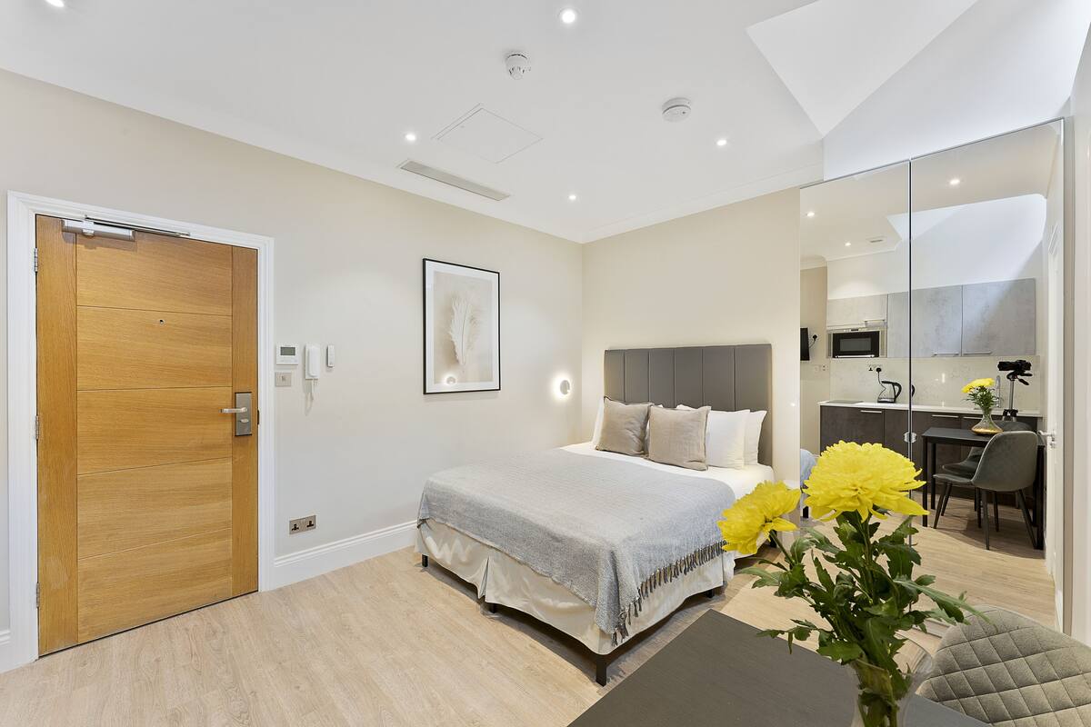 A modern bedroom with a bed, bedside table, and a desk area with a chair.