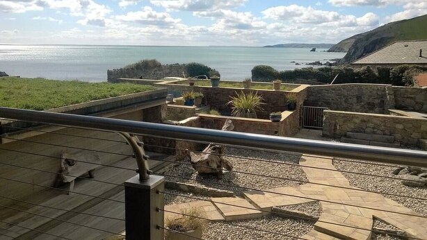 A terrace with a view of the sea, stone walls, and potted plants. - The Fish Cellars - Luxury Holiday Cottage (Portwrinkle)