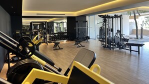 Un gimnasio moderno con diverso equipo de ejercicio, amplias ventanas y suelo de madera.