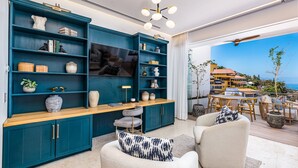 Una sala de estar moderna con muebles color turquesa, un televisor de pantalla plana y vistas a la costa.