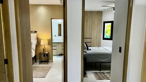 A modern bedroom with a bed, bedside table, lamp, and a view of a bathroom.