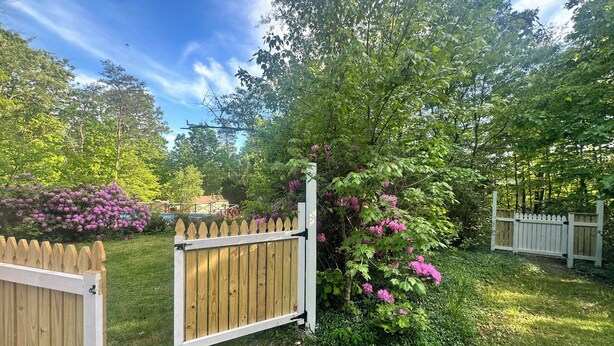 A wooden gate in a garden with lush greenery and flowering plants. - Rustic Tabor Woods Cabin near Cacapon State Park w/Patio, Grill (Berkeley Springs)