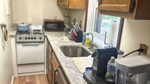 A compact kitchen with a stove, microwave, and sink. - Rustic Tabor Woods Cabin near Cacapon State Park w/Patio, Grill (Berkeley Springs)