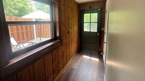 A hallway with wooden paneling, a door with a window, and a ceiling light fixture. - Rustic Tabor Woods Cabin near Cacapon State Park w/Patio, Grill (Berkeley Springs)