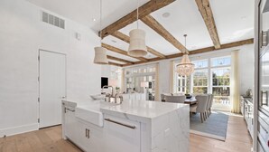 Una cocina moderna con una isla grande, vigas de madera y ventanas amplias.