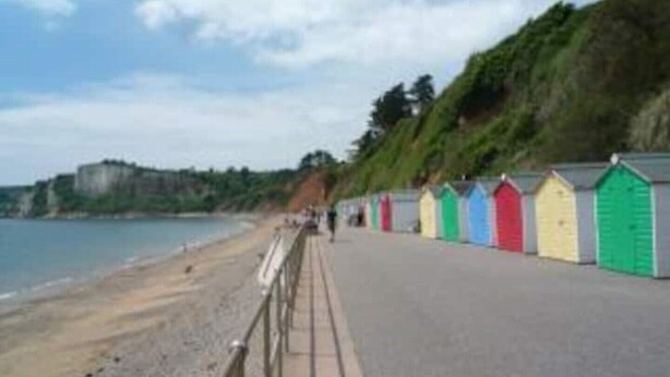 Una playa con cabañas de colores a lo largo de la orilla.