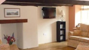 Una sala de estar con un sofá, sillones, un televisor y una estantería.
