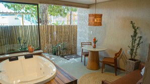 A modern bathroom with a large bathtub, wooden flooring, and a view of the outdoors through a large window. - Pousada Mansão da Costa (Maragogi)