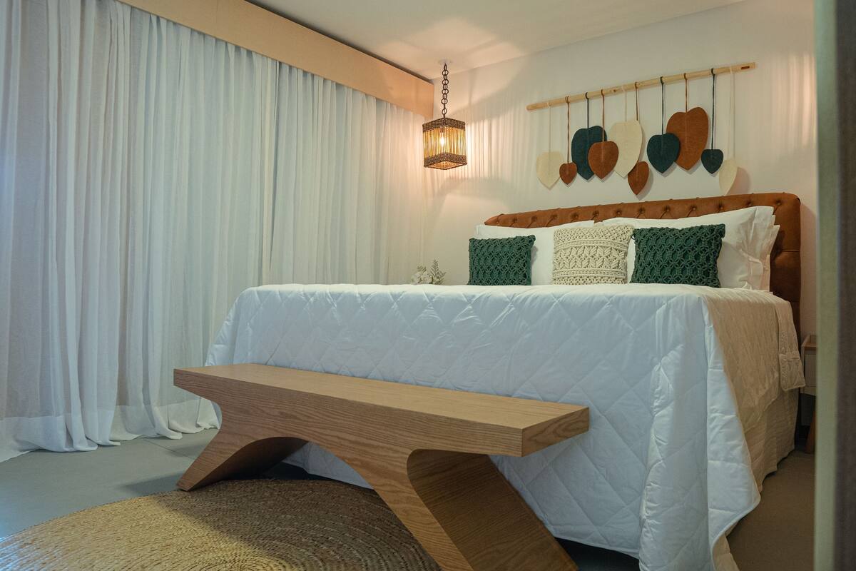 Ein Schlafzimmer mit einem Bett, einer hölzernen Bank, einer Pendelleuchte und einer Wand mit herzförmigen Verzierungen.