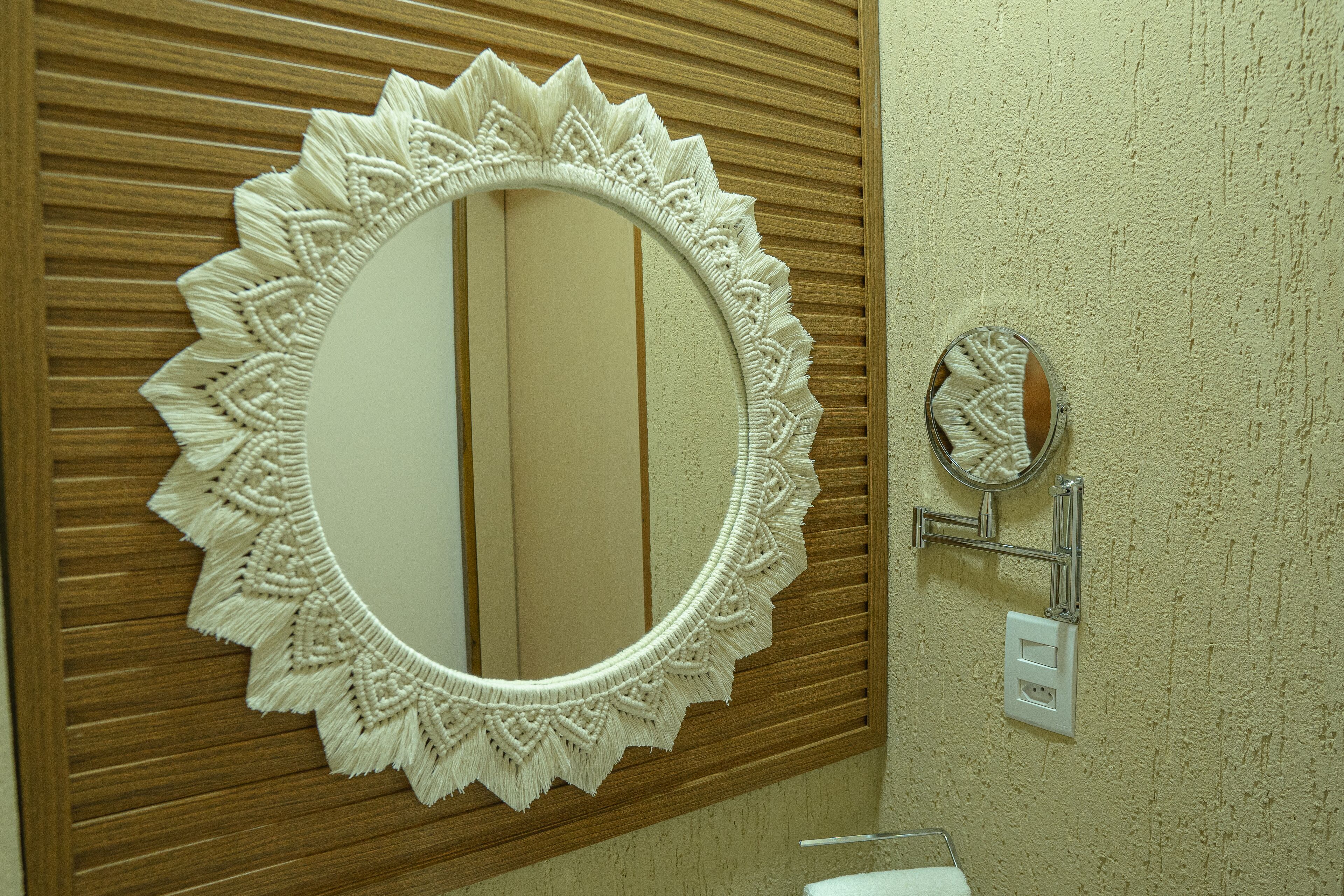 Une salle de bain avec un grand miroir, un mur recouvert de panneaux en bois et un petit miroir rond fixé au mur.