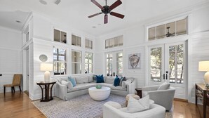 A spacious living room with a large sectional sofa, a round coffee table, and a ceiling fan.