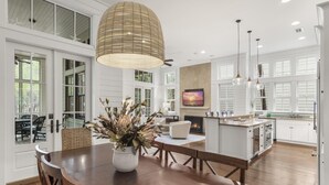 A spacious kitchen with a large island, white cabinetry, and a fireplace.