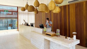 Een receptiegedeelte met een marmeren balie, rieten hanglampen en een houten wand.