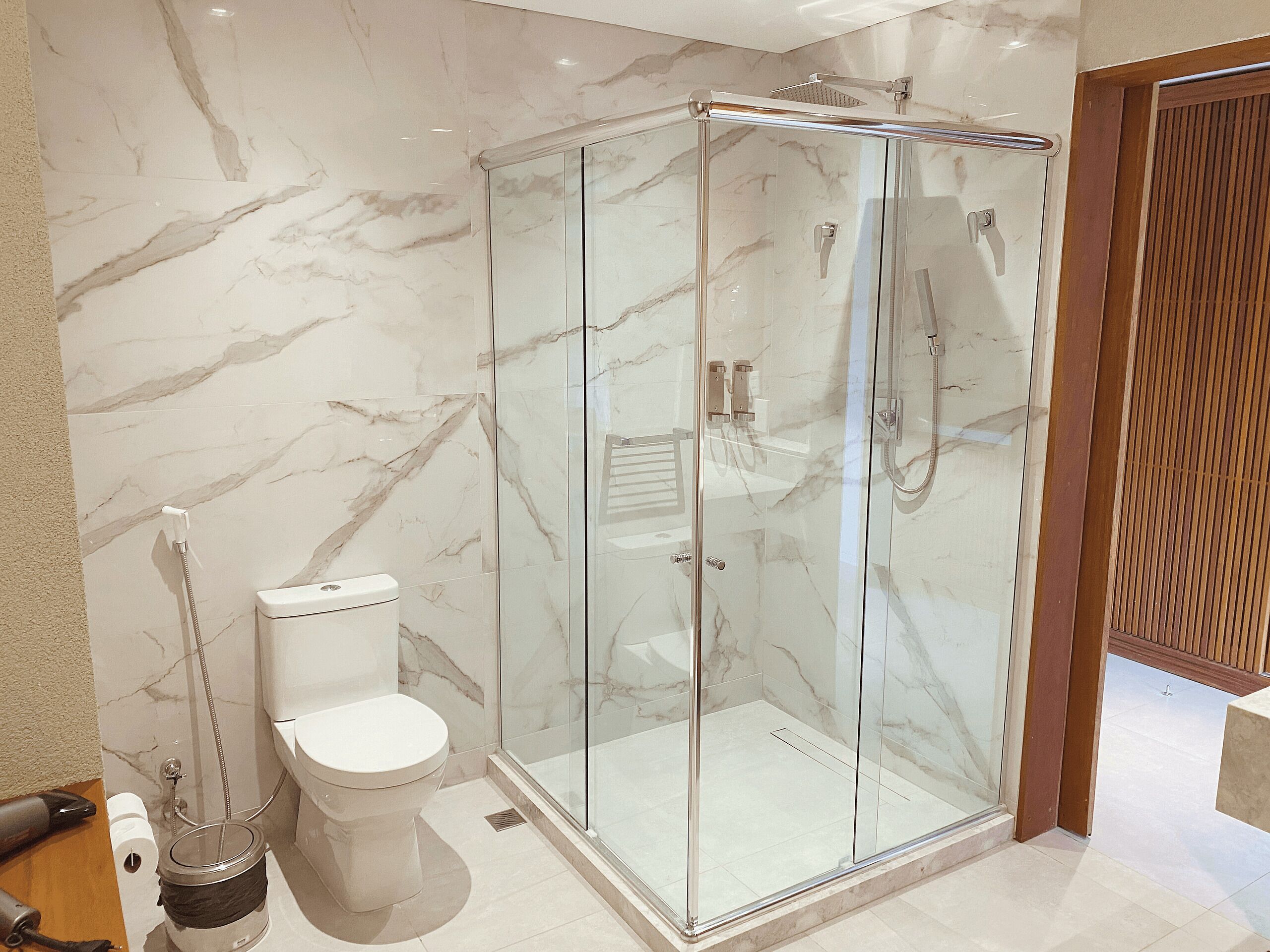 A modern bathroom with a glass-enclosed shower, a toilet, and a bidet.