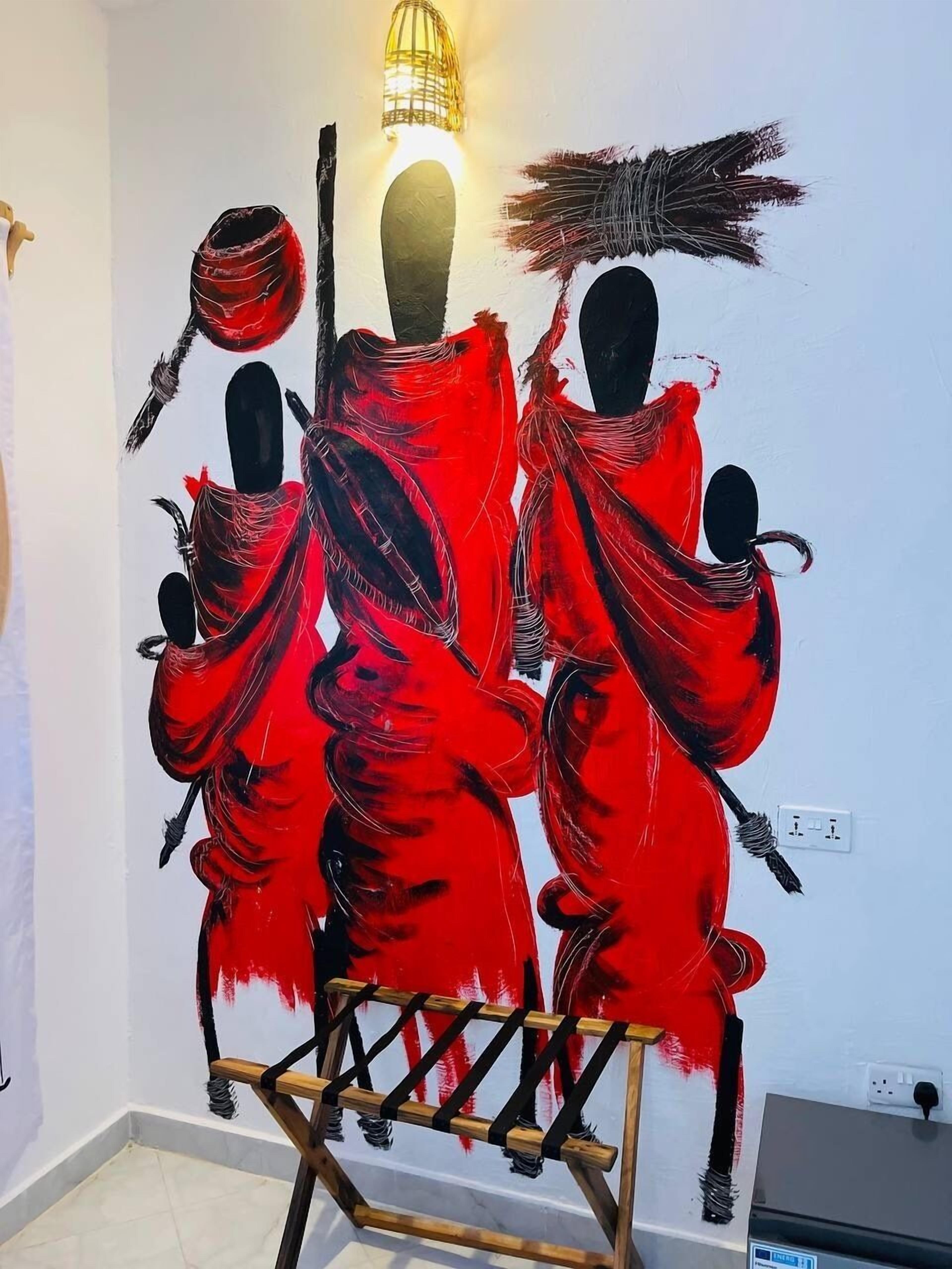 Une pièce avec un mur blanc et un tableau représentant trois personnages vêtus de robes rouges.
