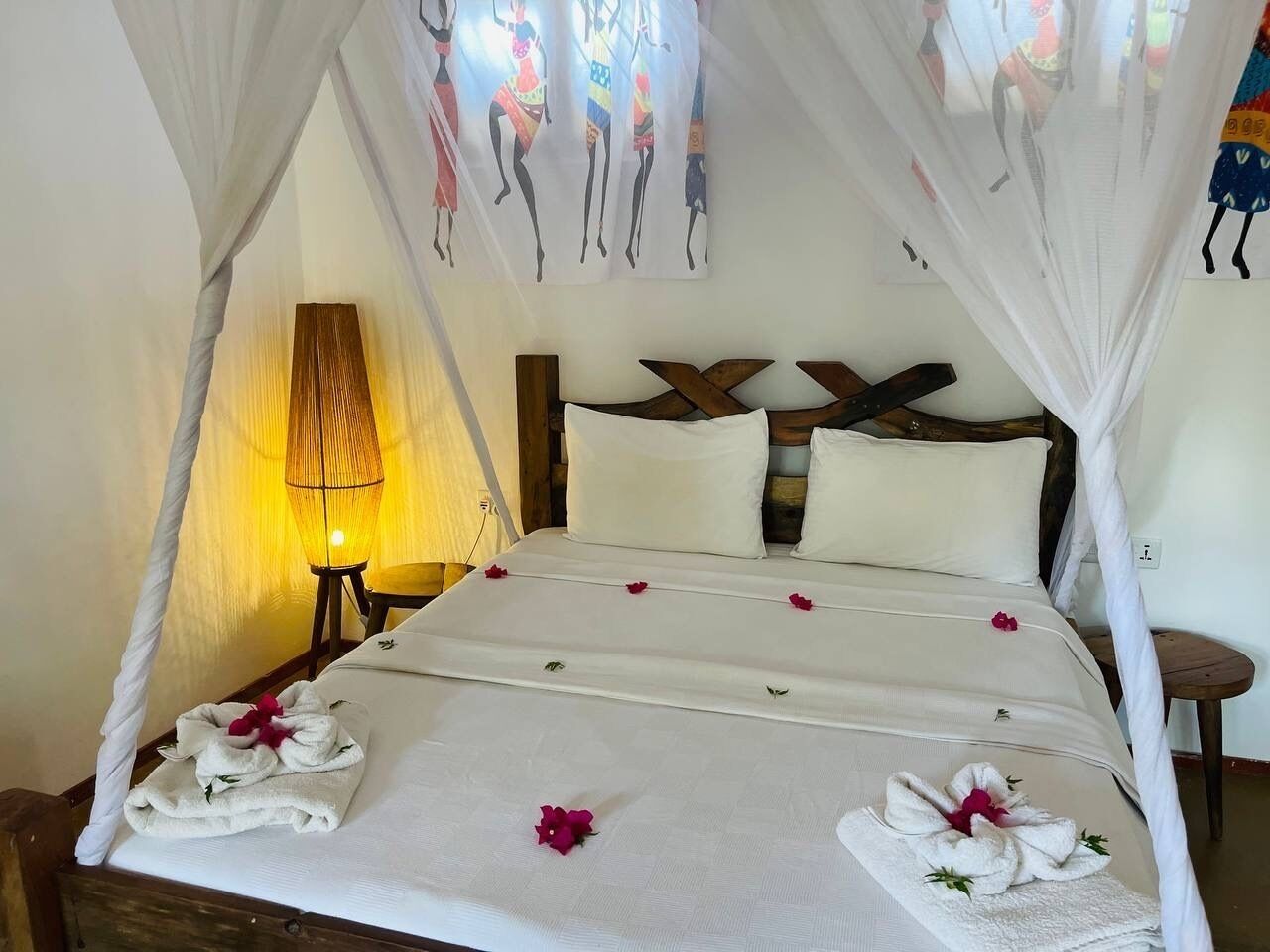 A bed with a canopy, white linens, and decorative pillows.
