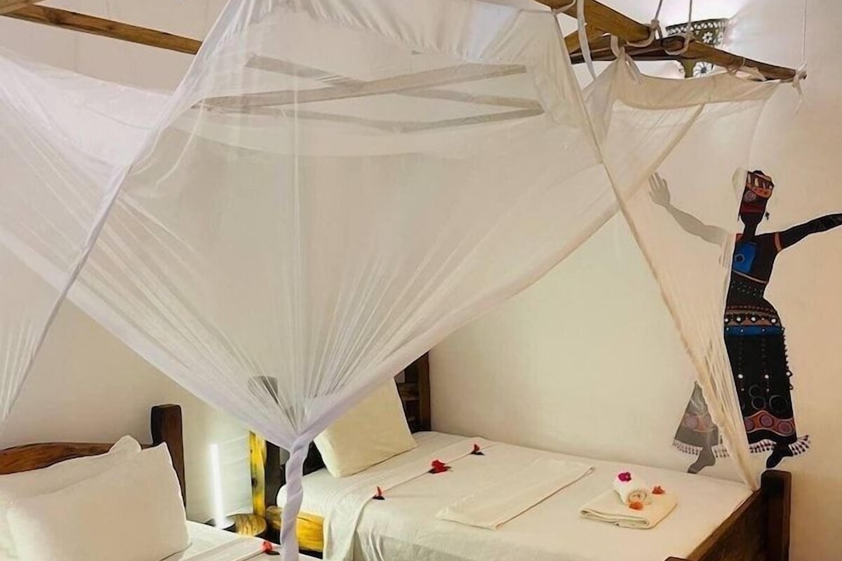 A room with two wooden beds, each with a canopy bedspread and pillows.